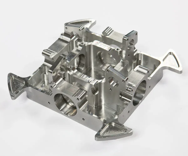 Precision CNC-machined aluminum engine block or multi-cylinder crankcase with four circular cylinder bores, complex internal webbing, mounting flanges, and lightweight cutouts at the corners, on white background.
