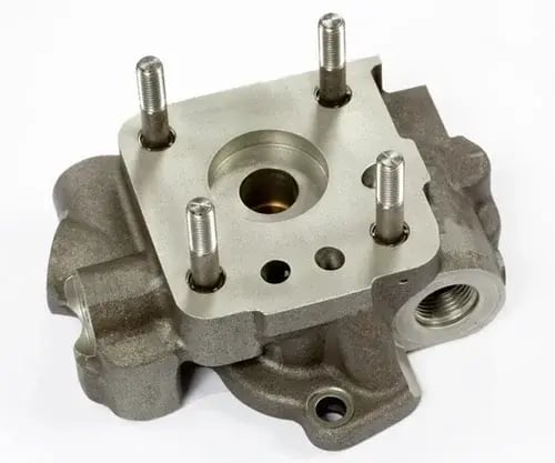 Manifold with six threaded studs, central bore, and multiple fluid ports, on white background.