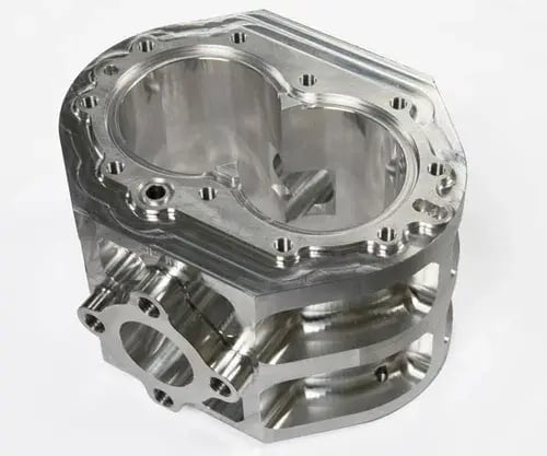 Precision CNC-machined aluminum gearbox with multiple bolt holes, large open cavity, and circular port, on white background.
