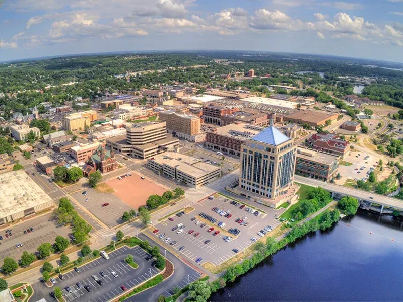 Aerial view of downtown Wausau, Wisconsin with the Wisconsin River and surrounding tree lined cityscape.